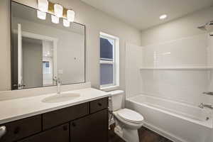 Bathroom featuring vanity, washtub / shower combination, dark wood-style floors, and recessed lighting