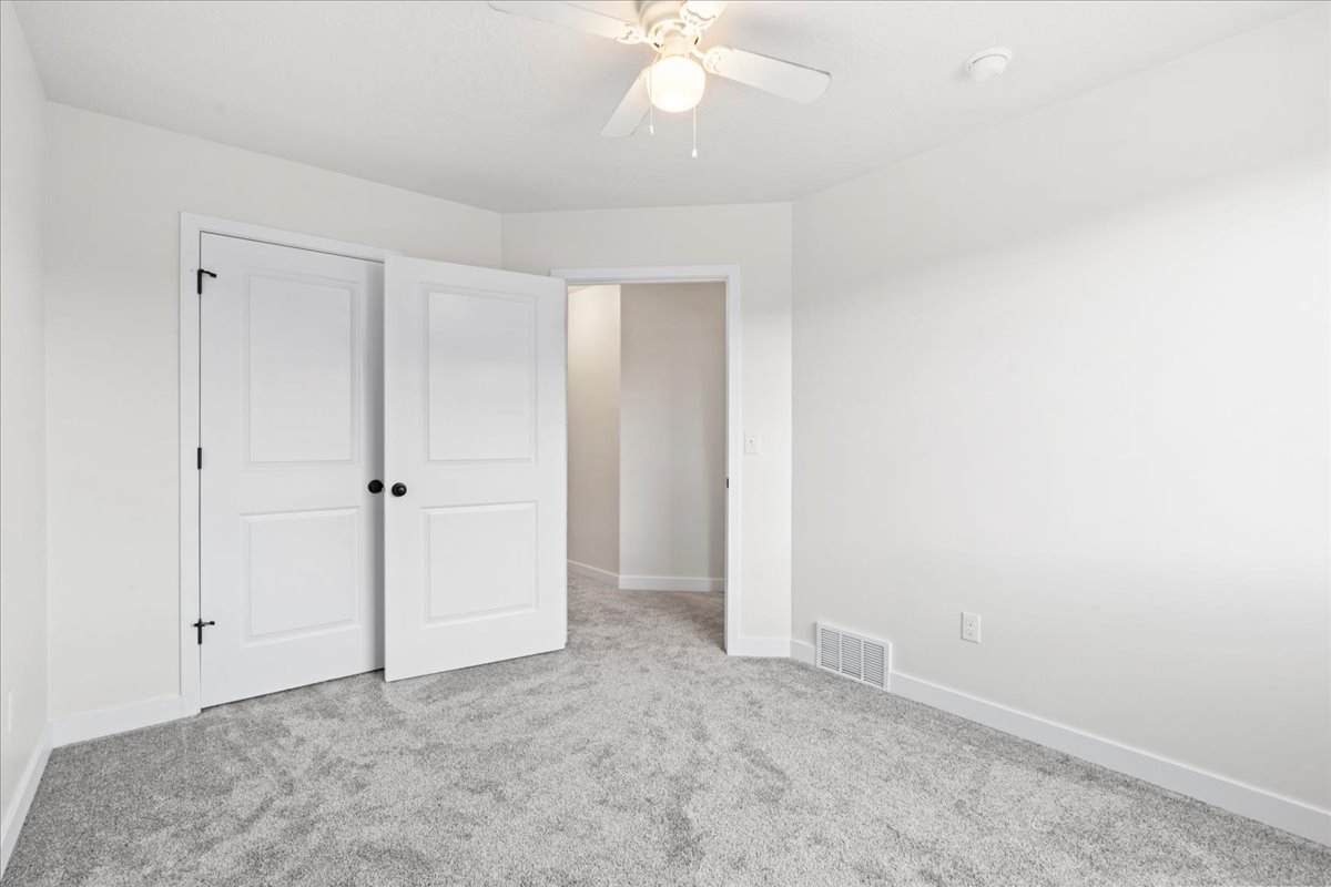 Unfurnished bedroom featuring light carpet and ceiling fan