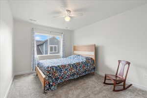 Bedroom with a ceiling fan, light carpet, and a textured ceiling