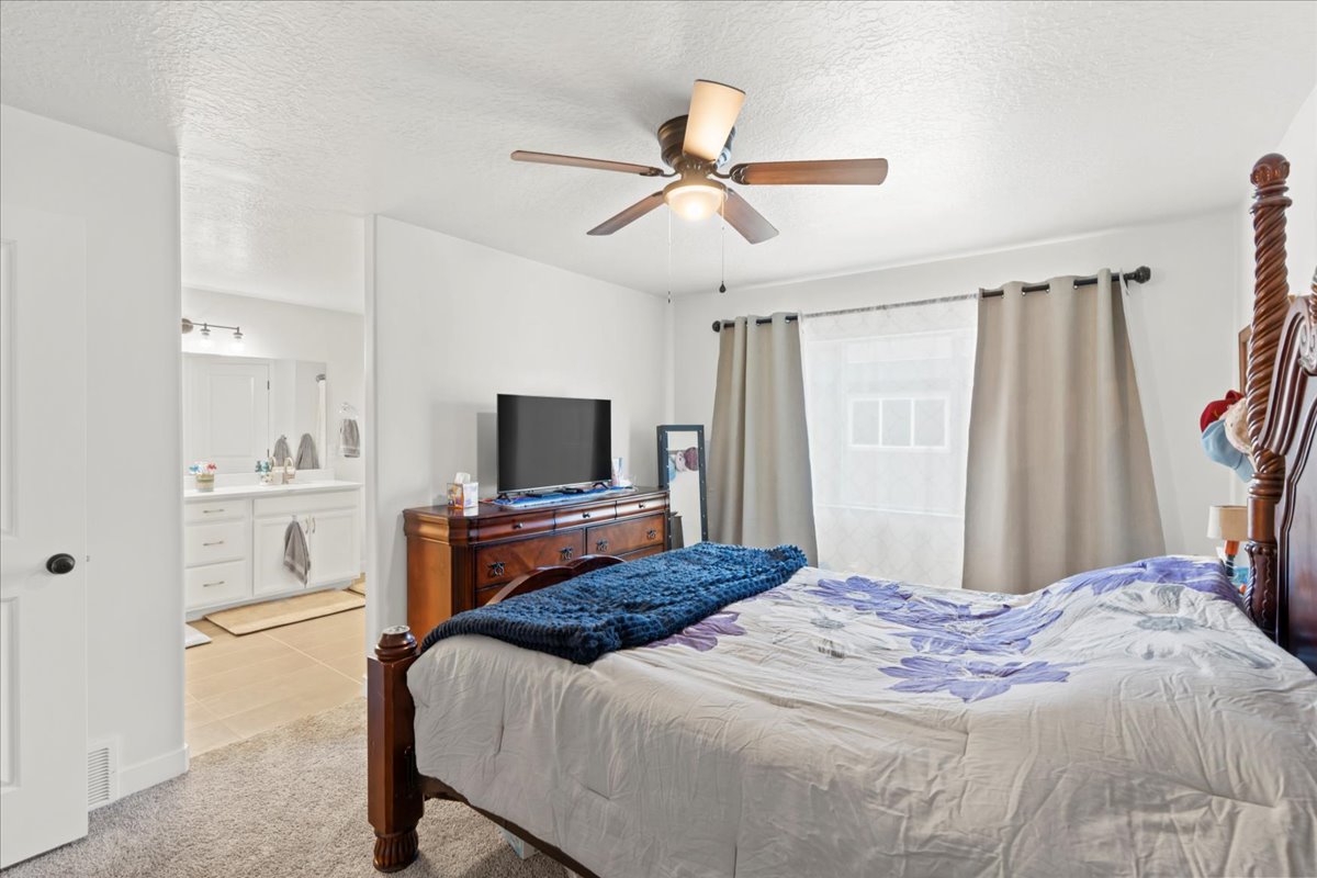 Bedroom with a textured ceiling, ceiling fan, and light colored carpet