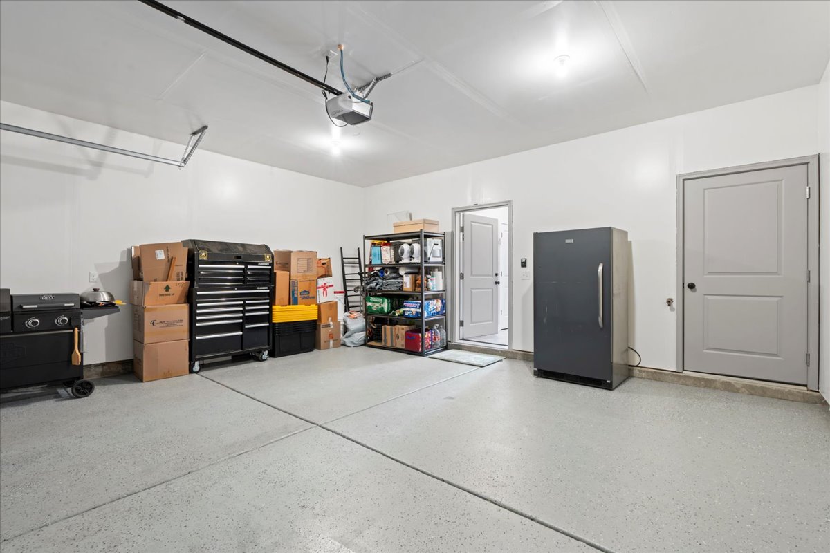 Garage featuring freestanding refrigerator and a garage door opener