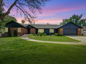View of front of house with board and batten siding, concrete driveway, a front lawn, and a garage