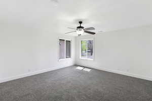 Unfurnished room with dark carpet and a ceiling fan