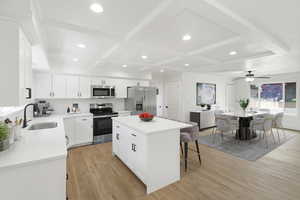 Kitchen featuring white cabinets, stainless steel appliances, a center island, light wood-style flooring, and a ceiling fan