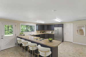 Kitchen featuring high end fridge, a peninsula, a breakfast bar area, a textured ceiling, and electric stovetop
