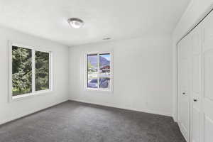 Unfurnished bedroom with a closet, dark carpet, and crown molding