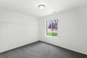 Empty room with a decorative wall, a wainscoted wall, and dark carpet