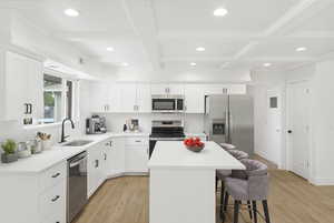 Kitchen with a center island, white cabinets, recessed lighting, stainless steel appliances, and coffered ceiling