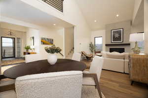 Dining space featuring a large fireplace, recessed lighting, wood finished floors, and lofted ceiling
