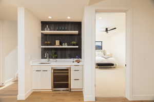 Indoor wet bar with modern cabinets, recessed lighting, open shelves, wine cooler, and light wood finished floors