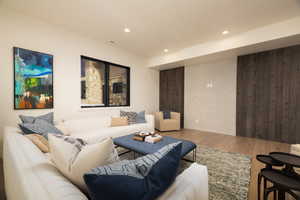 Living room with wood finished floors, wooden walls, and recessed lighting