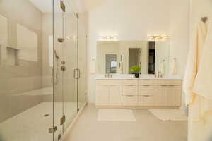 Bathroom featuring double vanity, a shower stall, and light tile patterned flooring