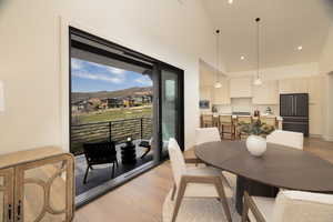 Dining space with light wood finished floors, a mountain view, a high ceiling, recessed lighting, and a residential view