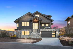 View of front of house featuring driveway, stone siding, and an attached garage