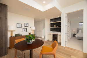 Dining room featuring wet bar, light wood-type flooring, wine cooler, and recessed lighting