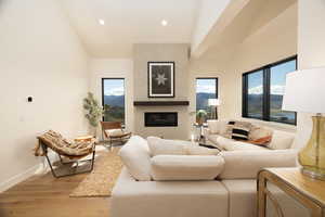 Living area featuring healthy amount of natural light, a mountain view, a large fireplace, hardwood / wood-style floors, and lofted ceiling