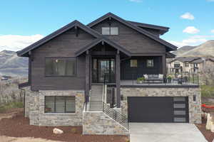 View of front of house with a mountain view, concrete driveway, a balcony, and an attached garage