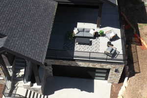 View of side of property with stone siding, a garage, driveway, and a patio area