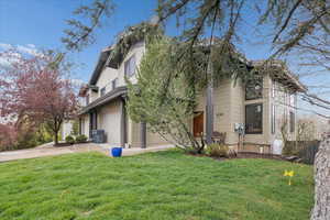 View of front of home with a front yard, an attached garage, and concrete driveway