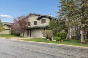 View of front facade featuring a front lawn, a garage, a chimney, and driveway