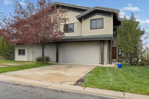 View of front of house with a front yard, a garage, and driveway