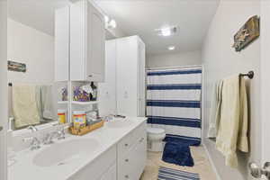 Full bathroom featuring double vanity, curtained shower, and light tile patterned floors
