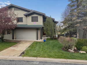 View of front of home featuring a garage, driveway, and a front yard