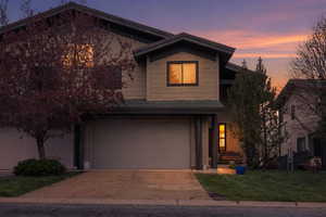 View of front of property featuring a garage, concrete driveway, and a lawn