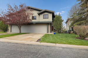 View of front of home with a front lawn, driveway, and an attached garage