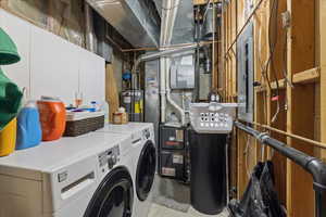 Laundry area featuring cabinet space, separate washer and dryer, water heater, heating unit, and electric panel