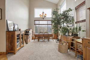 Office space with light colored carpet, lofted ceiling, hanging lights, and plenty of natural light