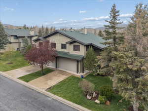 View of front facade with a garage, concrete driveway, a chimney, a front yard, and roof with shingles