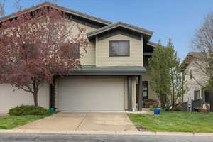 View of front of house with concrete driveway, a front yard, and an attached garage