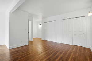 Spacious interior room featuring wood-finish flooring, white walls, and multiple white bi-fold closet doors