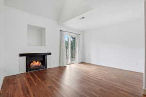 Living area with wood-finish flooring, a fireplace featuring a black mantel and white tile surround, and a recessed wall niche
