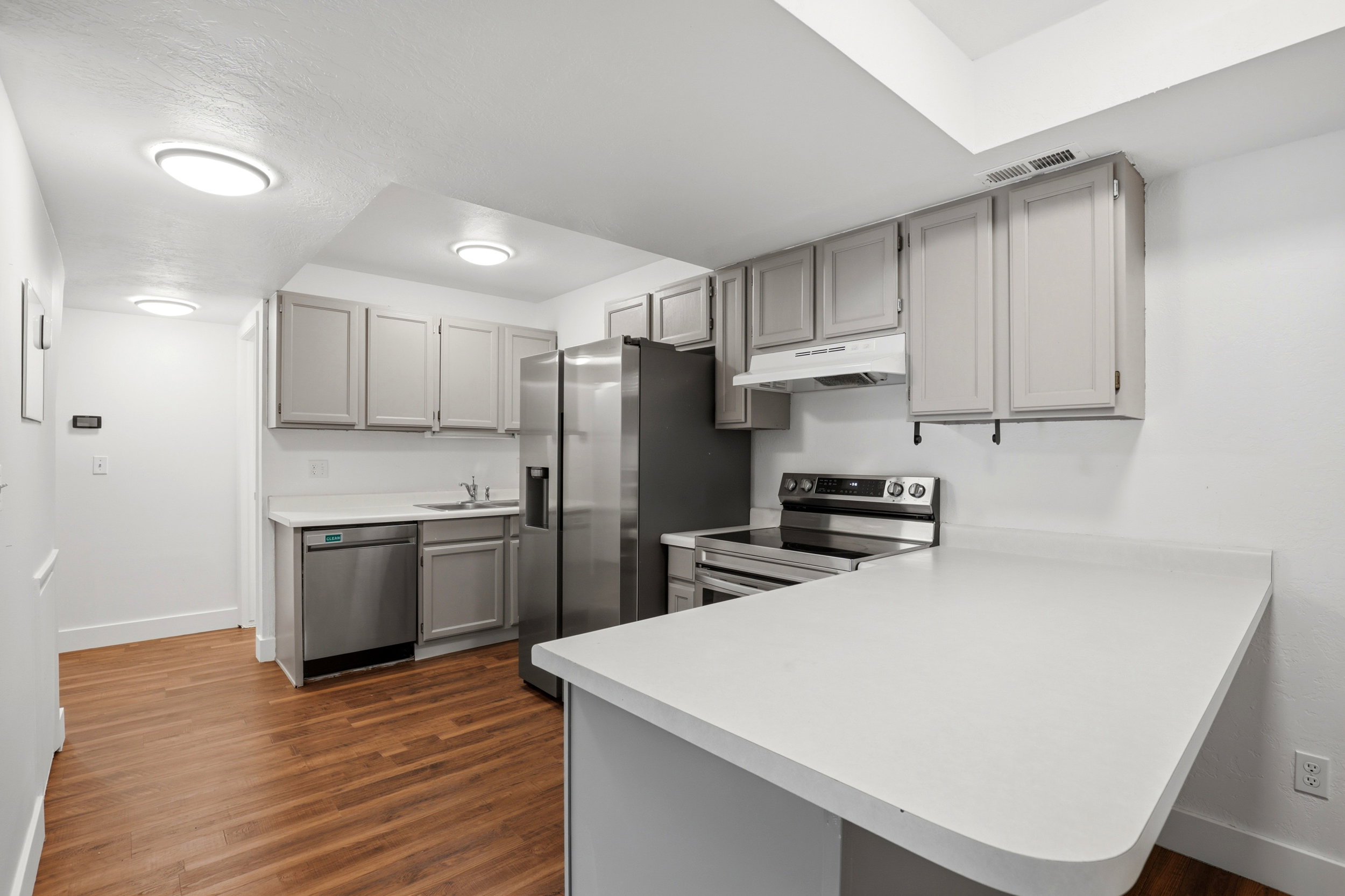 Kitchen featuring grey cabinetry, stainless steel appliances, wood-finish flooring, white countertops, and recessed lighting
