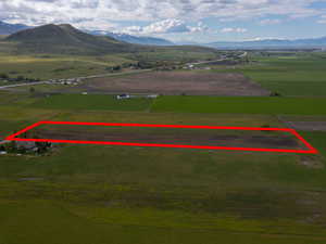 Aerial view of sparsely populated area featuring a mountainous background and large plots for crops