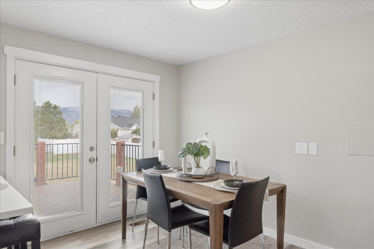 Dining space with french doors, light wood-style floors, and a textured ceiling