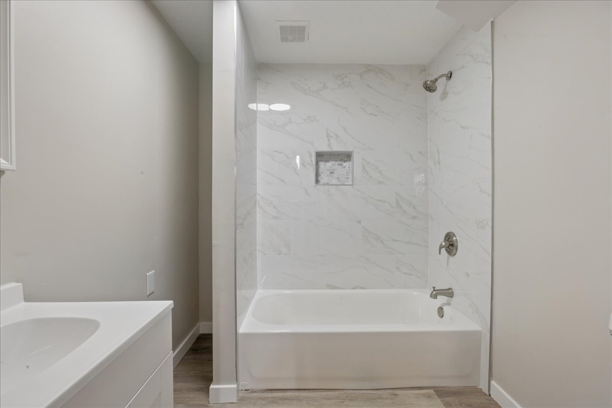Bathroom featuring vanity, light wood-type flooring, and washtub / shower combination