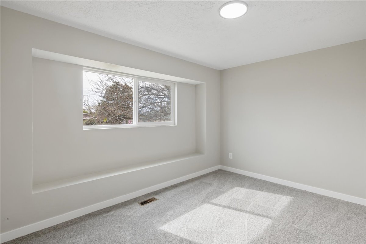 Empty room with light carpet and a textured ceiling