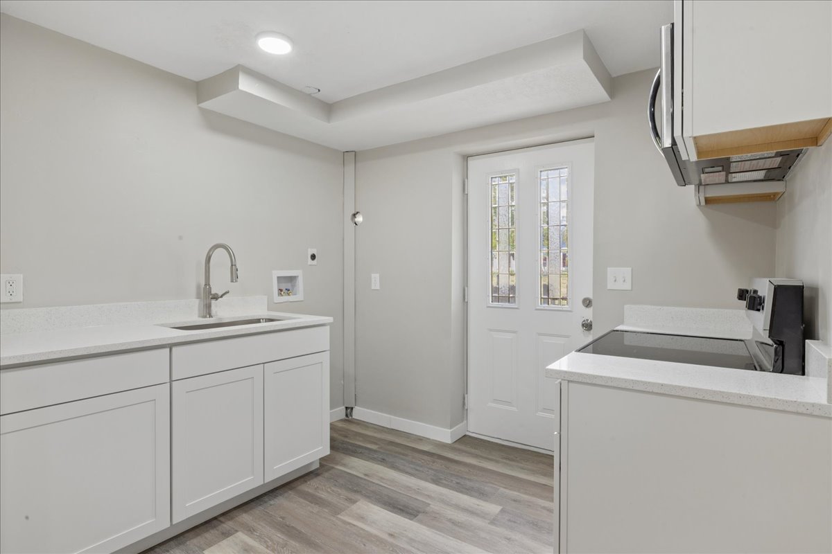 Laundry area featuring cabinet space, light wood finished floors, hookup for a washing machine, and recessed lighting