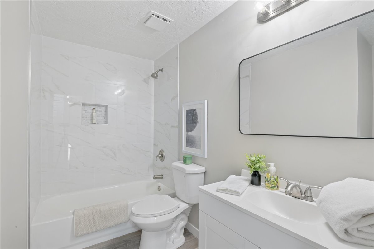 Full bathroom with vanity, bathing tub / shower combination, a textured ceiling, and light wood finished floors