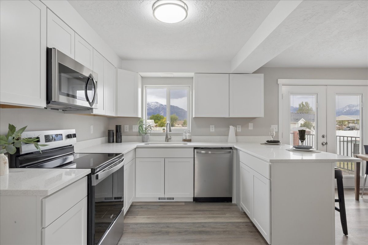 Kitchen with stainless steel appliances, a peninsula, a breakfast bar area, white cabinets, and a textured ceiling