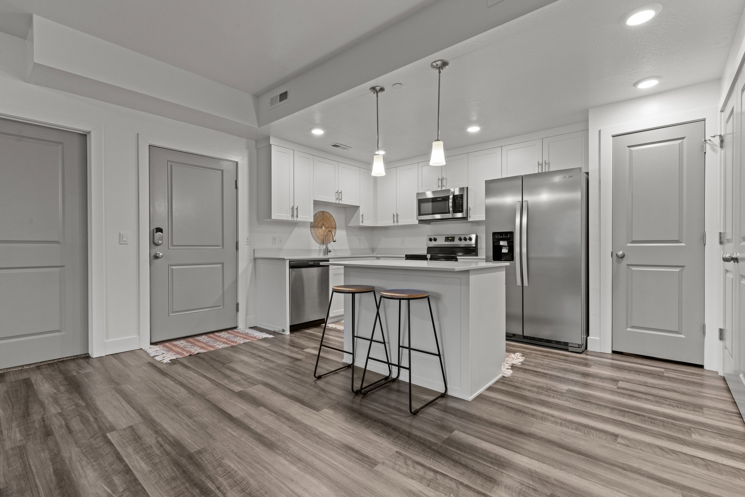 Kitchen featuring stainless steel appliances, a kitchen island, white cabinetry, a kitchen breakfast bar, and decorative light fixtures
