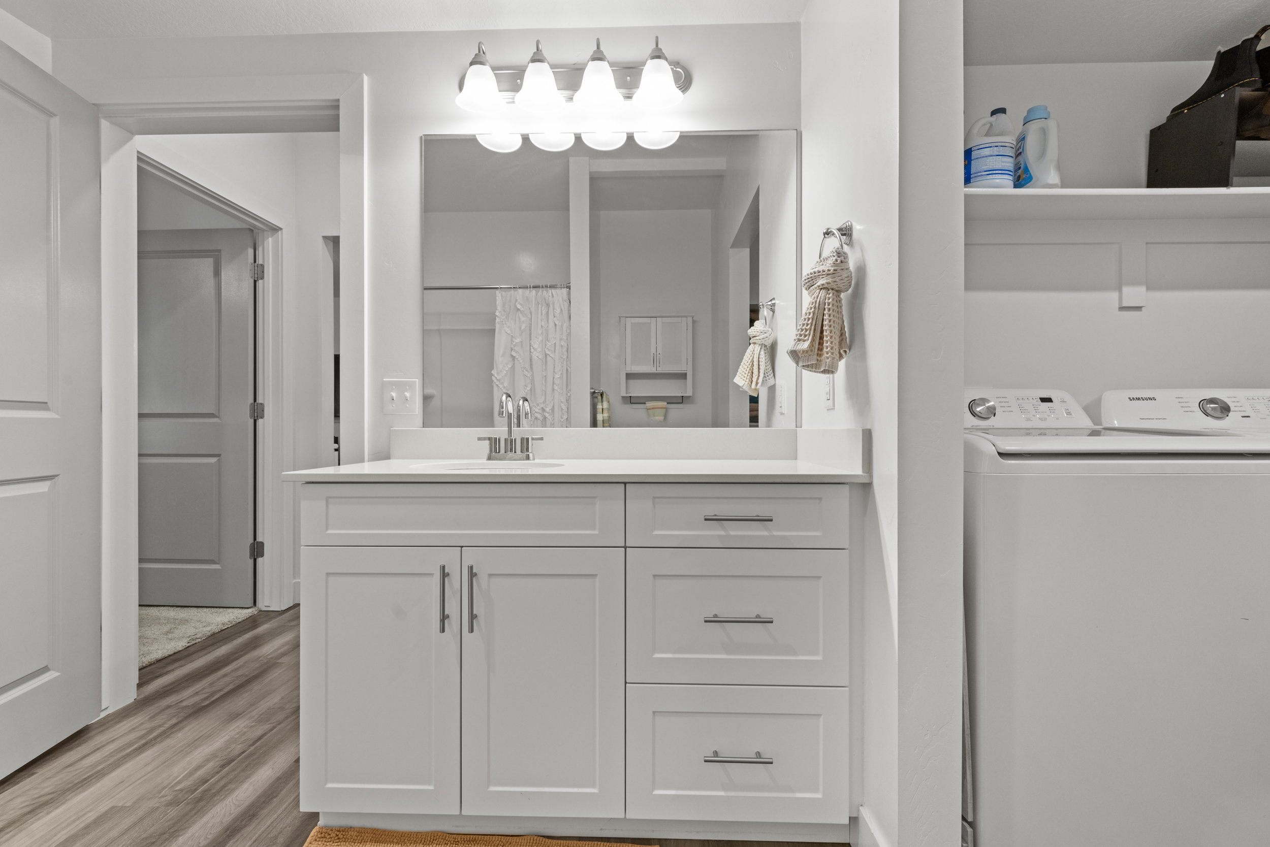 Full bath featuring vanity, curtained shower, light wood finished floors, and washing machine and dryer