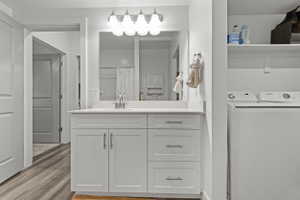Full bath featuring vanity, curtained shower, light wood finished floors, and washing machine and dryer