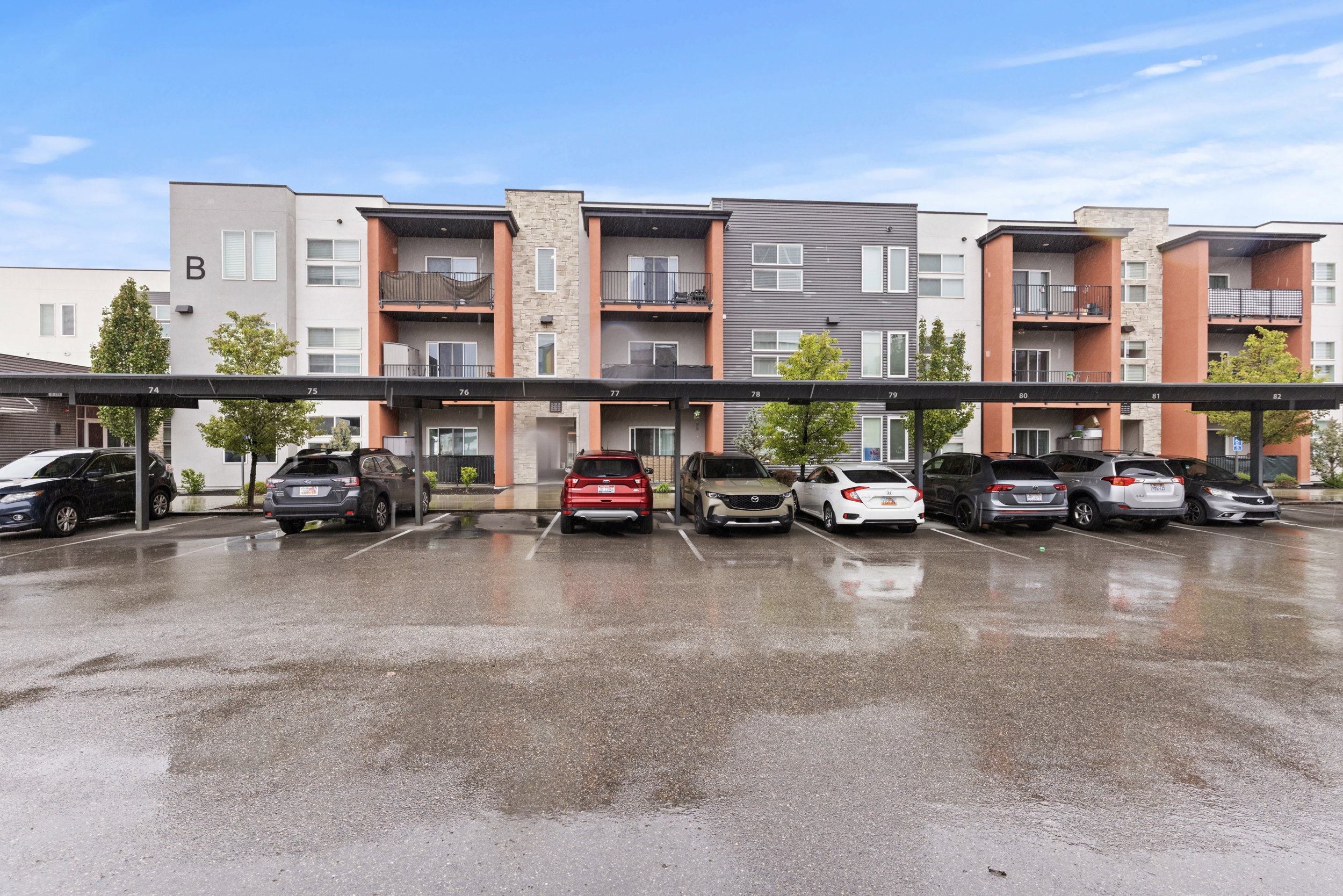 View of apartment building / complex featuring covered parking
