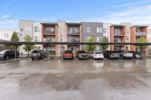 View of apartment building / complex featuring covered parking