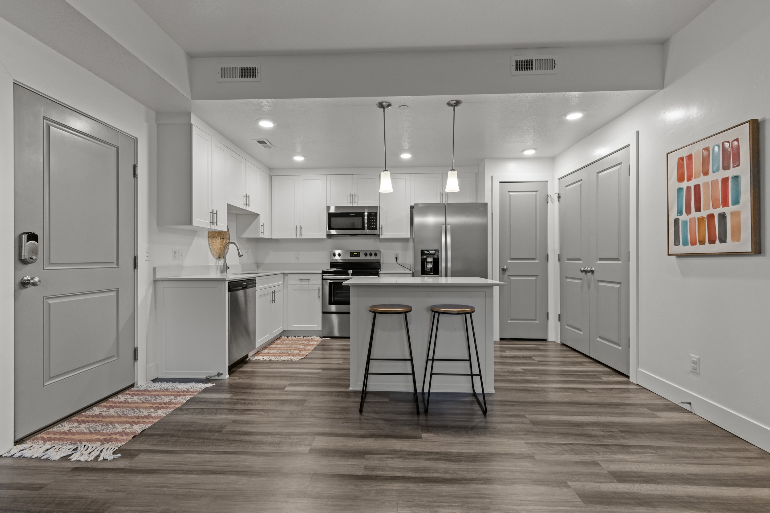Kitchen featuring light countertops, stainless steel appliances, a center island, white cabinets, and dark wood-style floors