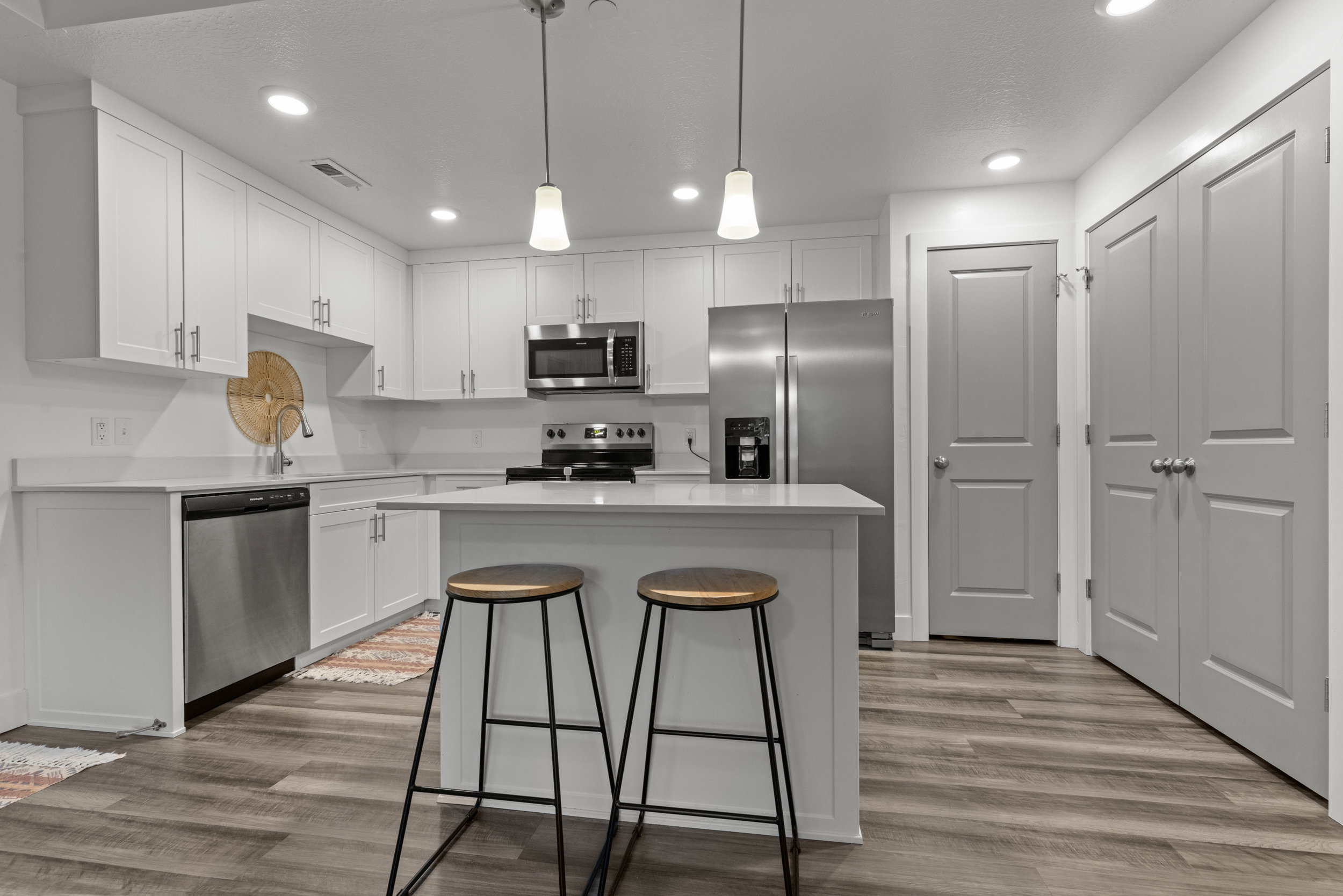 Kitchen featuring stainless steel appliances, a kitchen breakfast bar, a kitchen island, white cabinetry, and light wood-style floors
